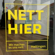 Ein gelber Aufkleber mit dem Slogan "Nett hier" auf einem Schaufenster