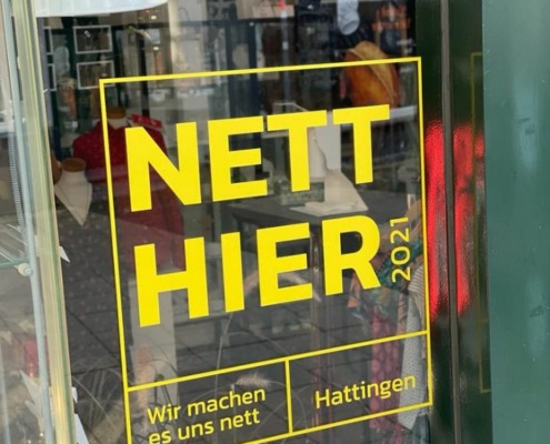Ein gelber Aufkleber mit dem Slogan "Nett hier" auf einem Schaufenster