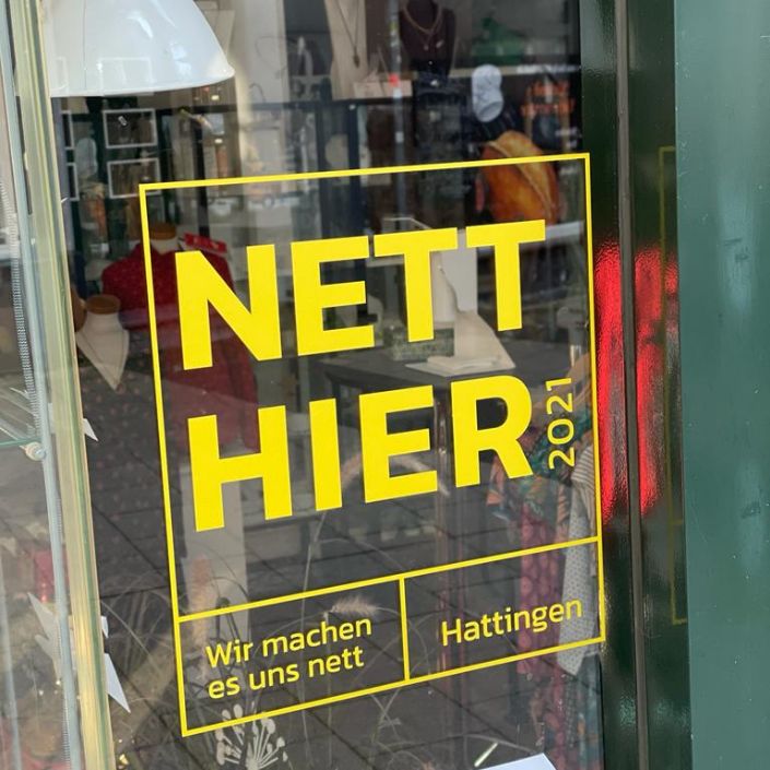 Ein gelber Aufkleber mit dem Slogan "Nett hier" auf einem Schaufenster