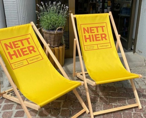 Zwei gelbe Liegestühle mit dem Slogan "Nett hier"