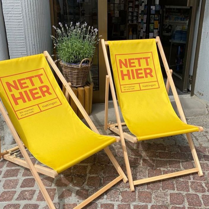Zwei gelbe Liegestühle mit dem Slogan "Nett hier"